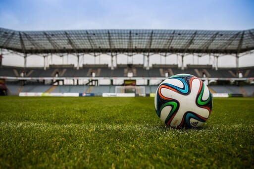 Soccer ball on pitch with empty stands